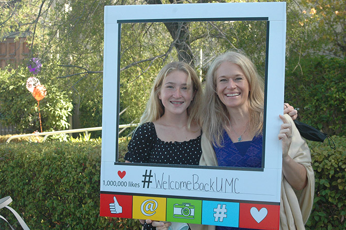 Smiling women with a sign saying Welcome Back UMC
